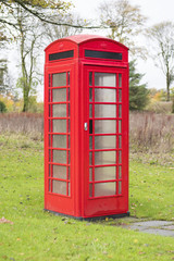 Single lone red old retro telephone box coin operated