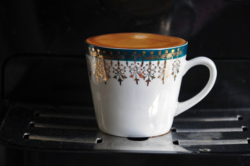 White mug with ornaments and fresh coffee.