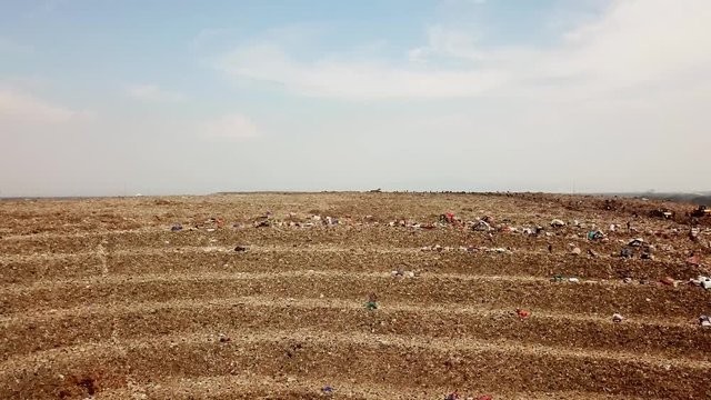 Pollution concept. Aerial shot of Bantar Gebang trash dump or landfill from a drone flying from left to right in Bekasi, Indonesia. Shot in 4k resolution