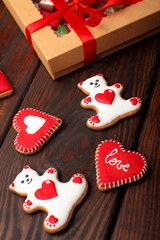 Two cookies of white bears with red heart and two cookies in a form of heart with inscription love and white heart.Box of cookies. Over wooden background.Valentine day background