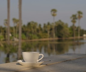 the coffee in the white glass is placed on a wooden counter on the terrace outside the field.
