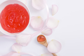Pink rose flower petals and red cream on white background for beauty cream. Beauty cream
