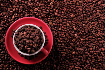 Red coffee cup and saucer one single for espresso or capuccino on a background of scattered dark coffee beans photo