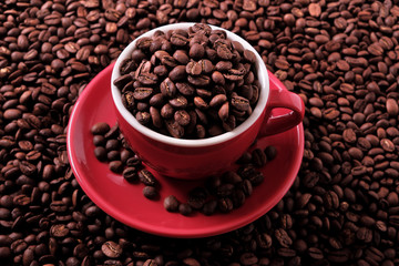 Red coffee cup and saucer one single for espresso or capuccino on a background of scattered dark coffee beans photo