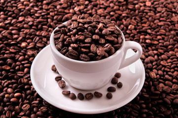 White coffee cup and saucer one single for espresso or capuccino on a background of scattered dark coffee beans photo