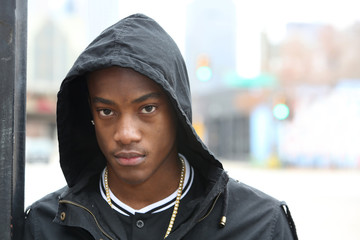 Street scene young African American male model  wearing hoodie against Dallas Texas skyline.