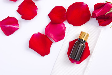Top view of rose flower petals with aromatherapy essential oil glass bottle on white background