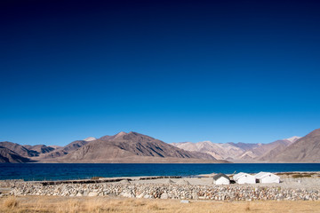 Fototapeta premium Landscape image of Pangong lake with small camps , mountains view and blue sky background
