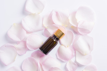Obraz na płótnie Canvas Aromatherapy oils with rose flower petals on white background. Top view. 