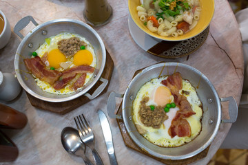 Eggs, bacon, green peas and minced pork cooked and served in small pan is popular breakfast menu in many restaurants in Thailand.