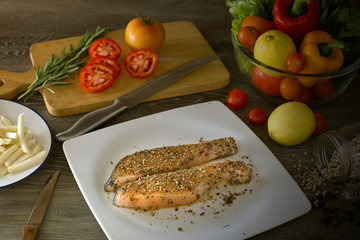 Prepare grill salmon with pepper and salt in white dish and ingredient in kitchen which has dim...