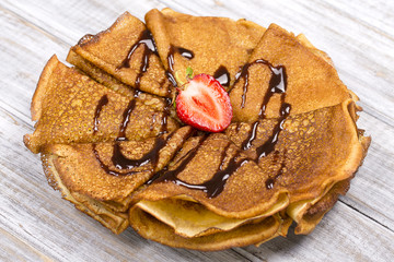 Pancakes with cottage cheese, strawberry, chocolate on the wooden table
