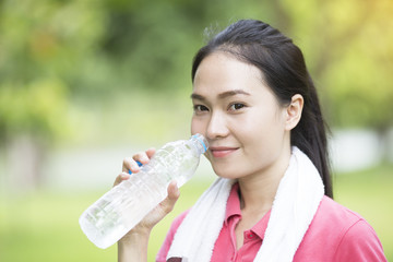 sporty woman drinking water from a bottle after jogging or running, sport and healthy concept