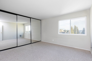 Bedroom empty, with mirror closet and new carpet for virtual staging.