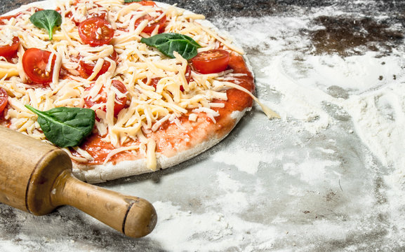 Unprepared pizza with ingredients.