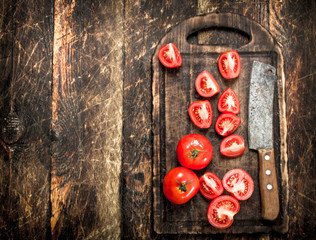 Fresh tomatoes with old hatchet on a chopping Board.
