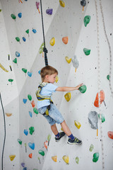 Fototapeta premium Child climbing on a high wall