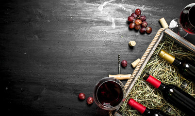 Wine background. Red wine in an old box with a corkscrew.