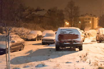 Snow covered car after snowfall in night city