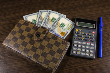 Notebook with dollars, pen and calculator on office desk