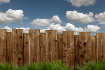 brauner Holzzaun im Garten bei blauem Himmel mit Wolken
