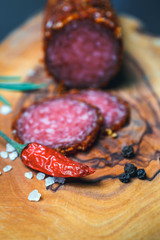 Dried salami crusted in ground red pepper on dark background