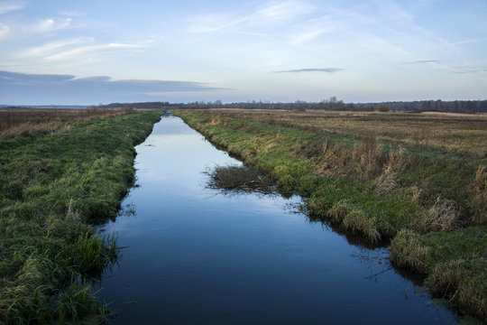 Long And Straight River, Wild Meadows And Large Forest.