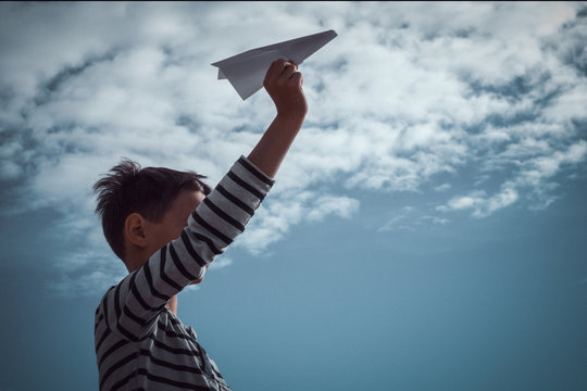 Boy throwing white paper plane.