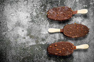 Fresh ice cream on a stick in chocolate with nuts.
