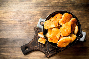 Chicken nuggets in a bowl on the board.