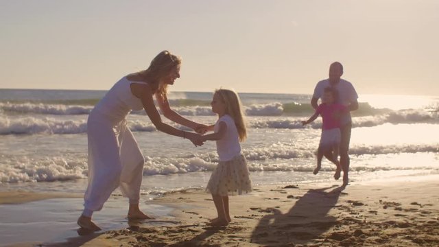 Young family playing and twirling on beach