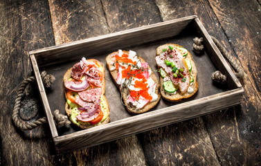 Sandwiches with seafood, salami, bacon and fresh vegetables.