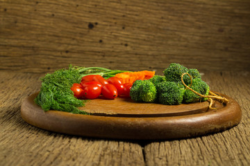 dill. baby tomatoes. carrot. broccoli. on old chopping borad wooden. on old wooden kitchen