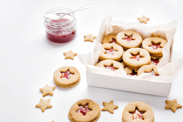 Cookies with raspberry jam on a table. Gingerbread in box on a white background. Star and round shape