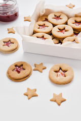 Cookies with raspberry jam on a table. Gingerbread in box on a white background. Star and round shape