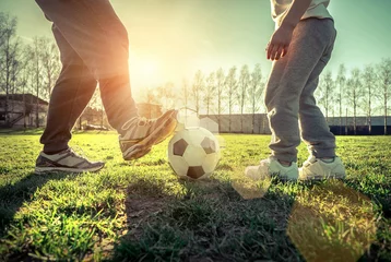 Foto op Aluminium Father and son playing together with ball in football under sun © Andrii IURLOV