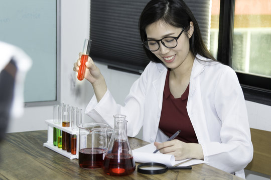 Young female scientist doing experiments in lab. Pretty female scientist testing tube with a long glass pipette in the scientific chemical laboratory.