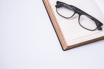 An open notebook with glasses on white background. Free space for text