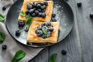 Plate with tasty blueberry pastries on wooden table