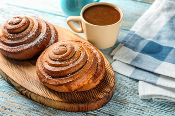Wooden board with sweet cinnamon rolls on table