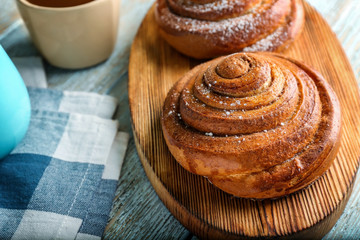 Wooden board with sweet cinnamon rolls on table