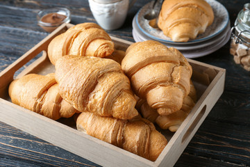 Tray with fresh yummy croissants on wooden table