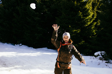Woman is having fun by throwing a snow ball during a hike in the forest/ Black Forest/ Germany
