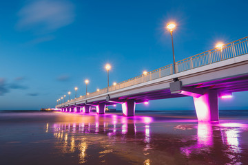 illuminated concrete pier in Kolobrzeg, long exposure shot at sunset