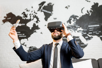 Businessman using virtual reality glasses sitting indoors with world map on the background