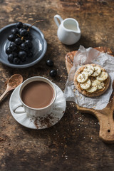 Cocoa, cracker with peanut butter, banana, flax  and chia seed, grapes - snack, breakfast table. Cosy atmosphere breakfast on wooden background, top view
