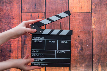 Clapper plates, women's hands and film clapper on a wooden background