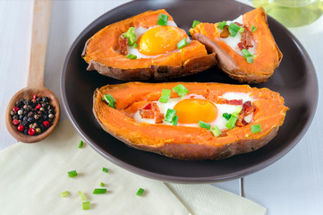 Baked sweet potato with fried egg, bacon and chives.