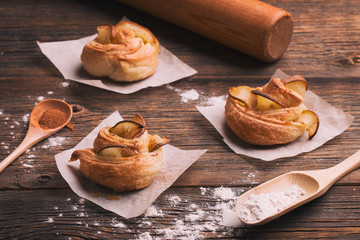 Fresh pastries with pear and cinnamon on a wooden background