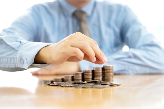 Businessman Sitting at Desk and Stacking Coins